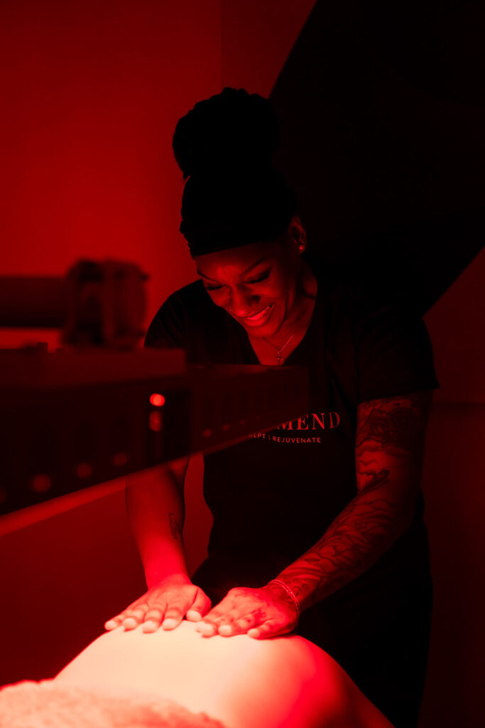 A professional practitioner at Sugar and Mend performing bespoke body work under restorative red light.